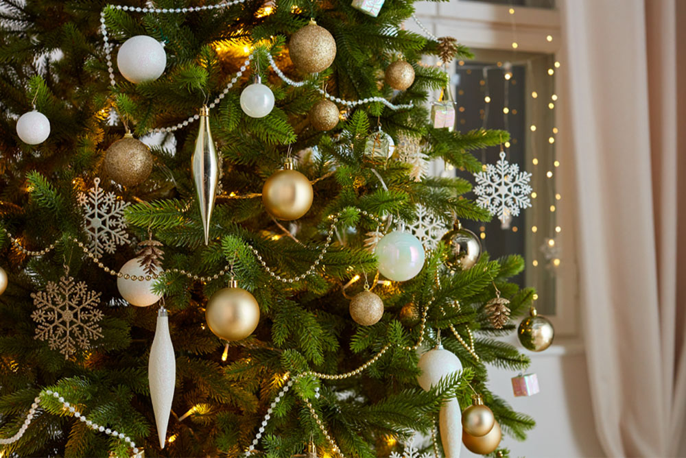 Božično drevo z okraski v zlati, srebrni in beli barvi.