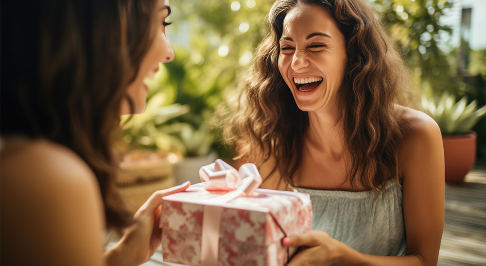 Nasmejana ženska podari darilo prijatelju.