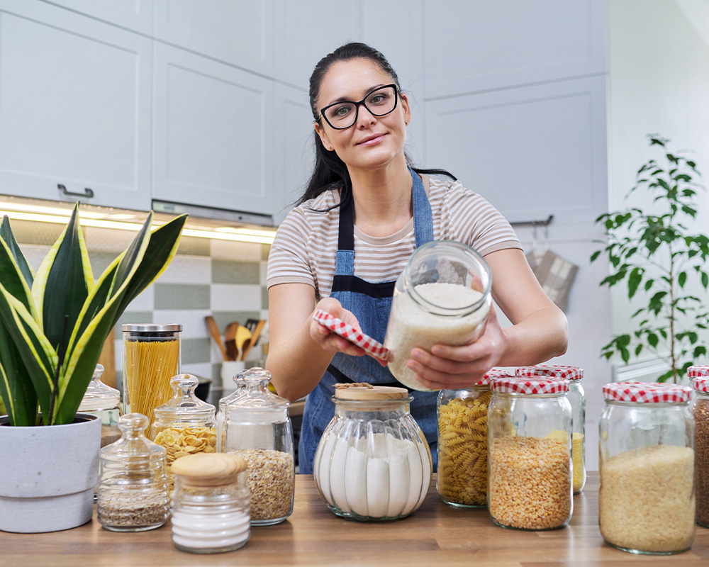 Ženska v kuhinji prikazuje kozarce za shranjevanje suhih živil