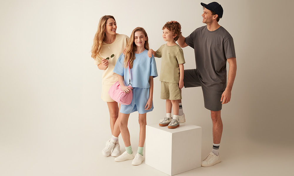 Družina v pastelnih oblačilih skupaj pozira na svetlem ozadju.